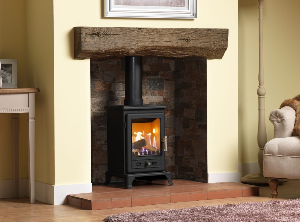 Rustic freestanding gas stove fireplace with a wooden mantel, available from Blue Oak Fireplaces in Leicester